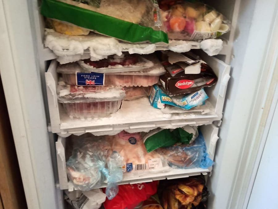A full freezer drawer stacked with frozen food, holding temperature.