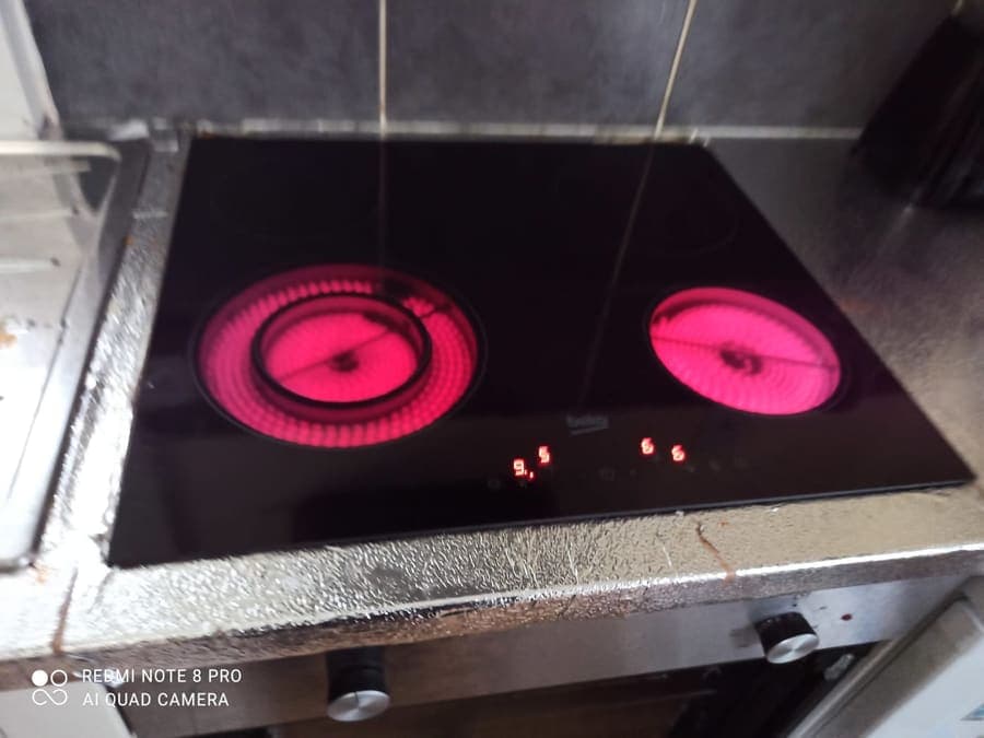 A ceramic hob with two rings glowing red, tested after a repair.